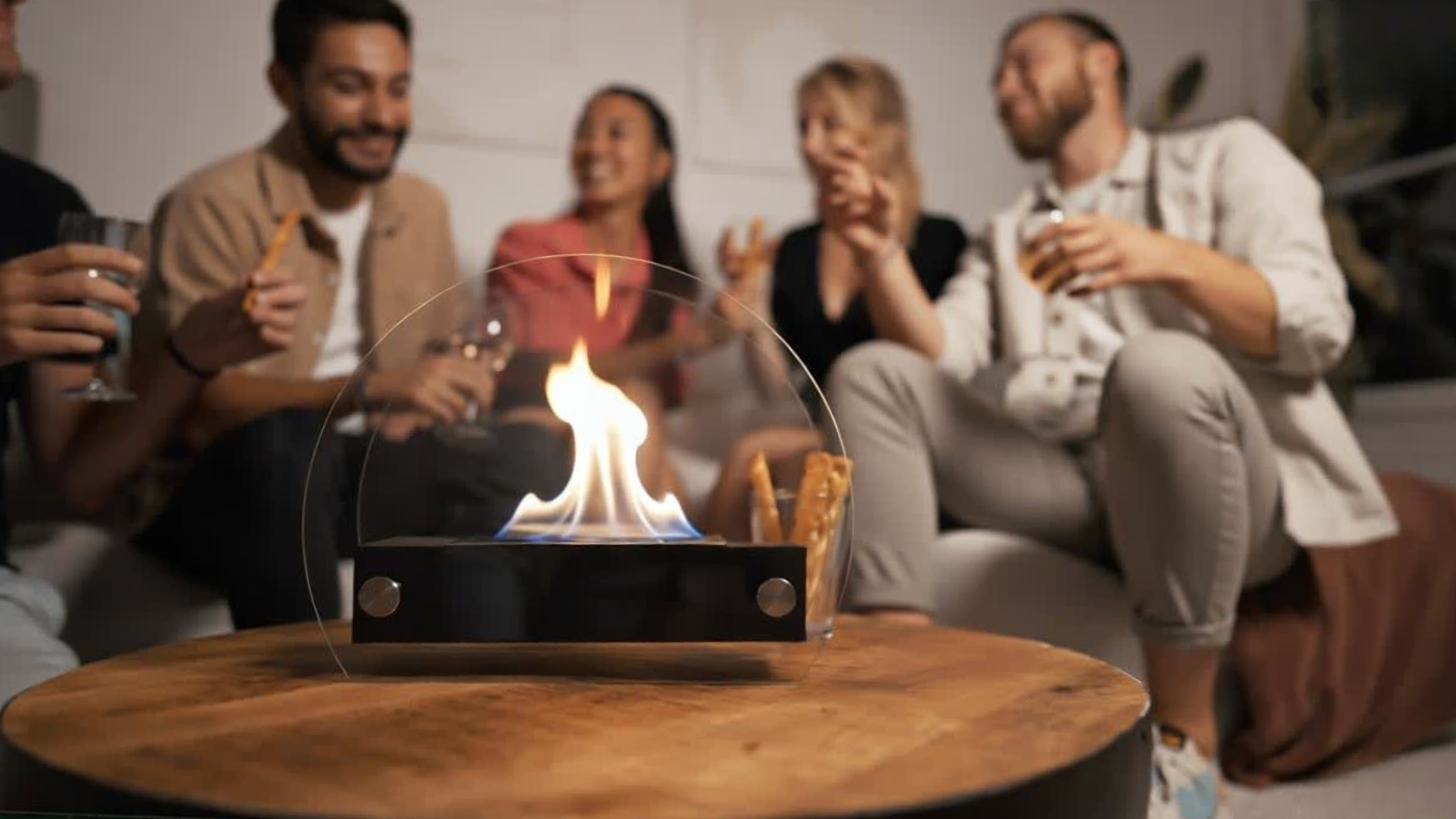 Cheminée de table au bioéthanol allumée sur une table basse, entourée d’amis dans une ambiance chaleureuse et conviviale